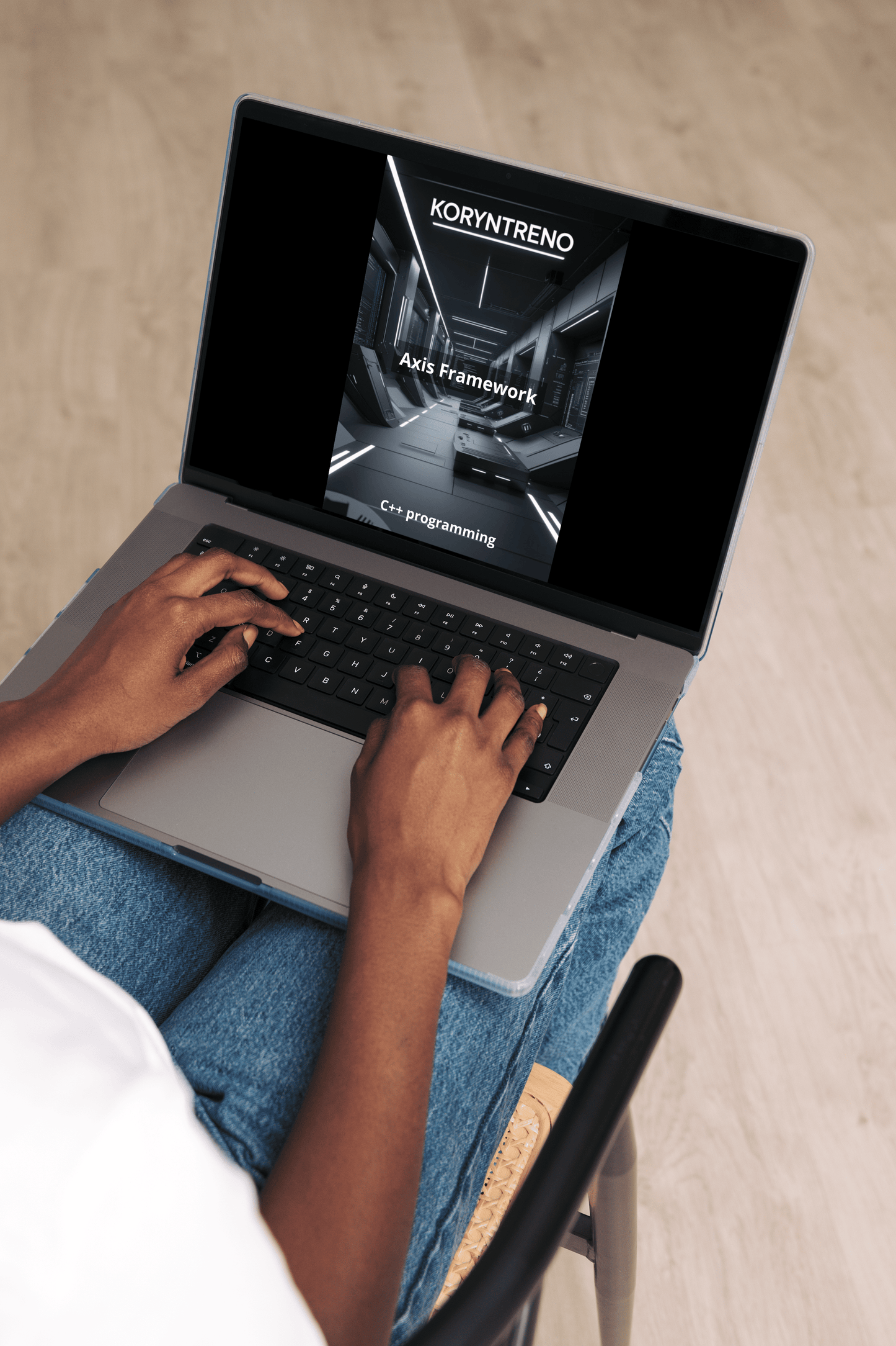 Person using a laptop with a C++ course on the screen, sitting on a chair.