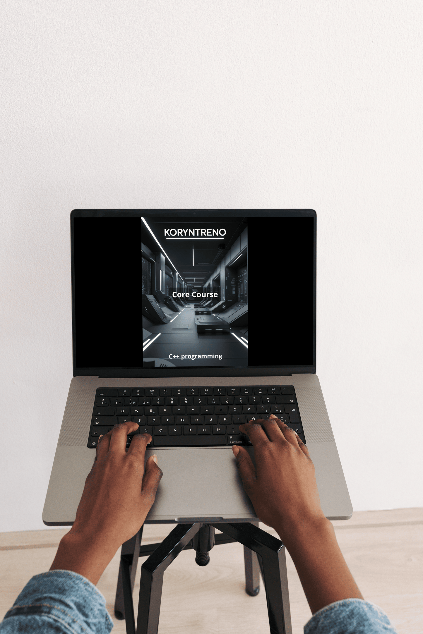 Person using a laptop with a screen displaying 'Koryntreno' C++ course on a white background