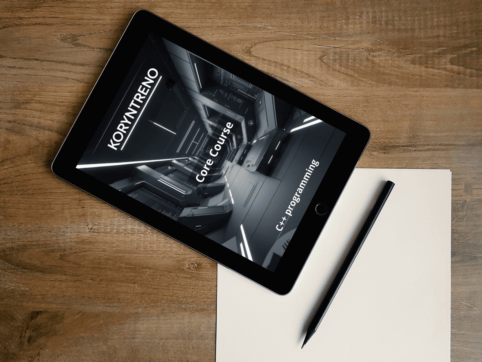 Tablet displaying a Koryntreno C++ course on a wooden surface with a pen and paper.