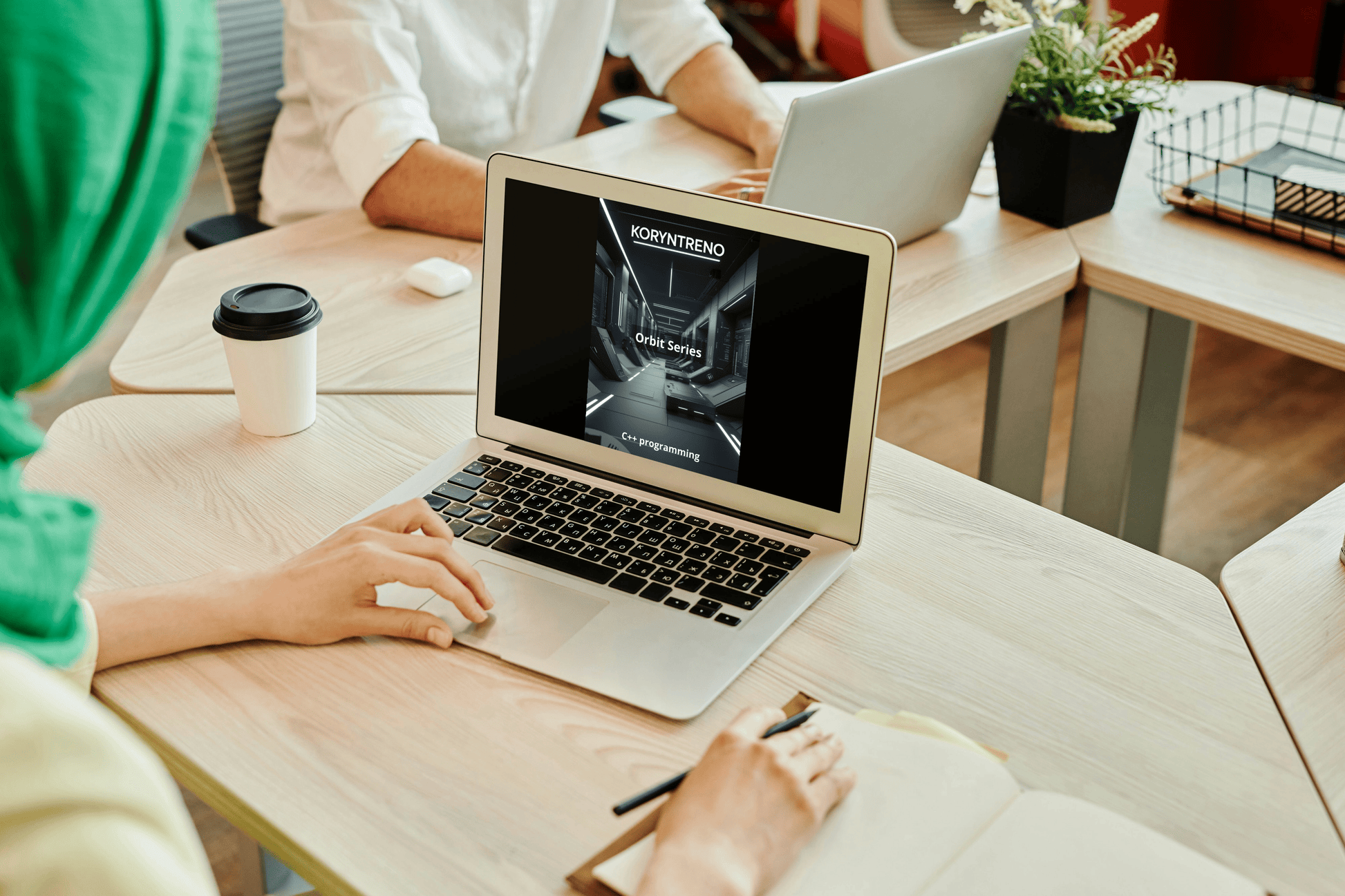 Person using a laptop with a C++ course in an office setting