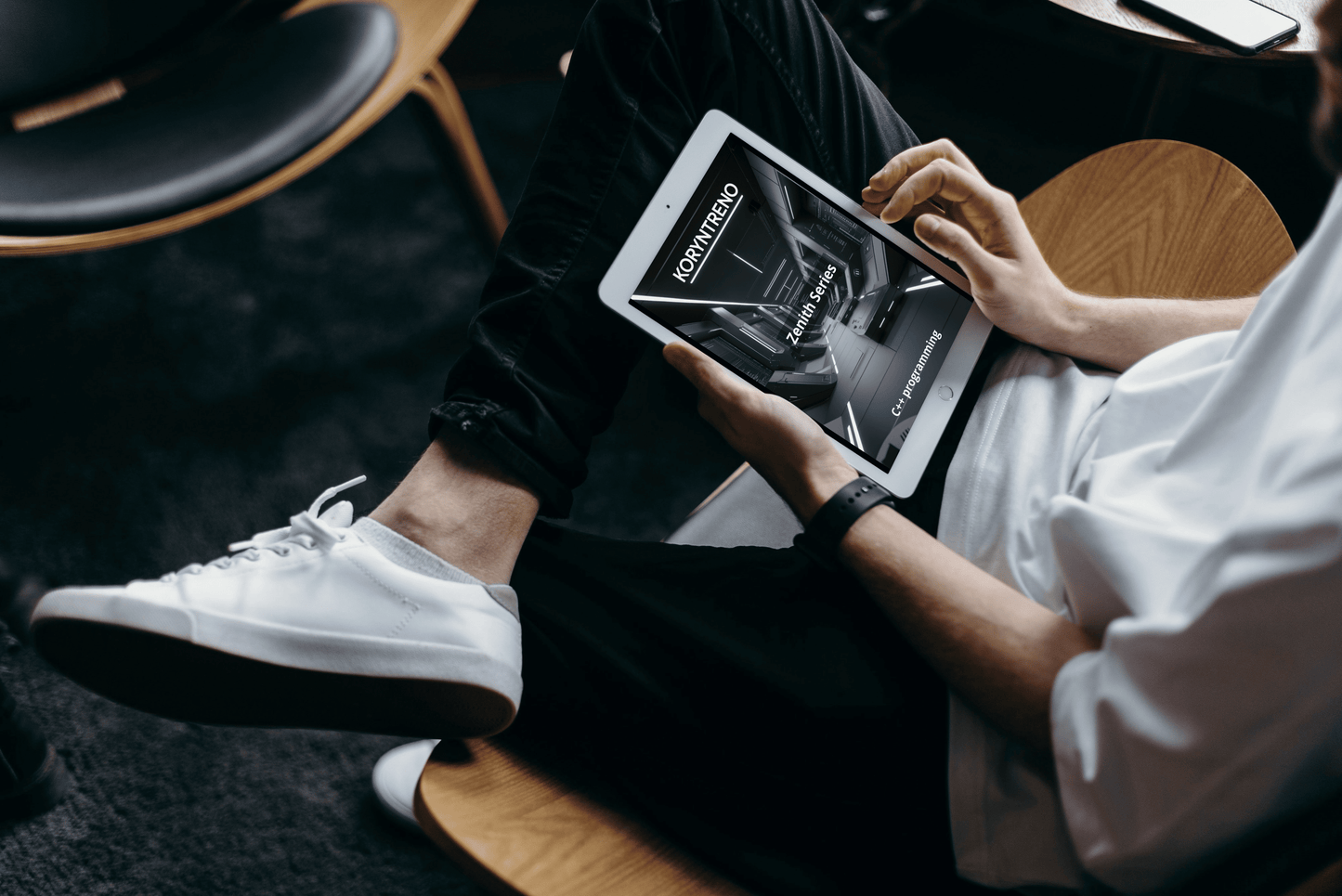 Person sitting on a chair holding a tablet with a C++ course 'Zenith Series'